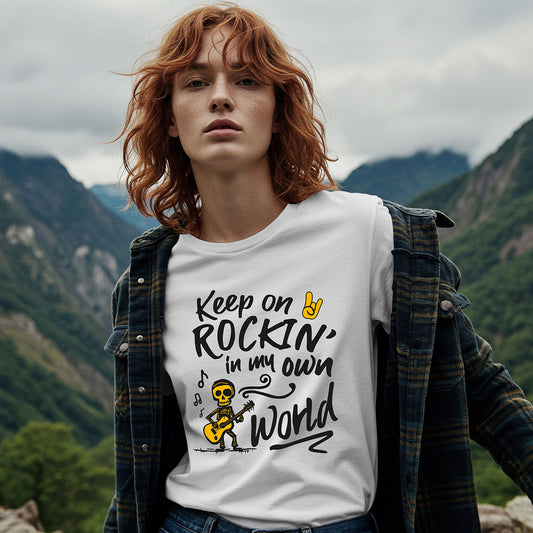 Person wearing a white t-shirt with a motivational quote and graphic, standing against a mountainous background.