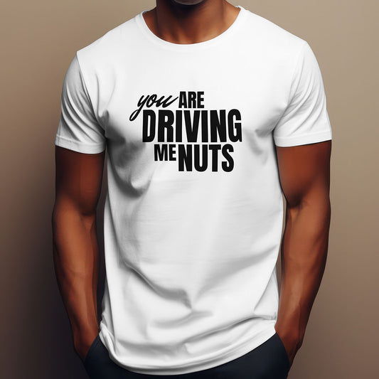 White t-shirt with black text 'you ARE DRIVING ME NUTS' worn by a person on a brown background