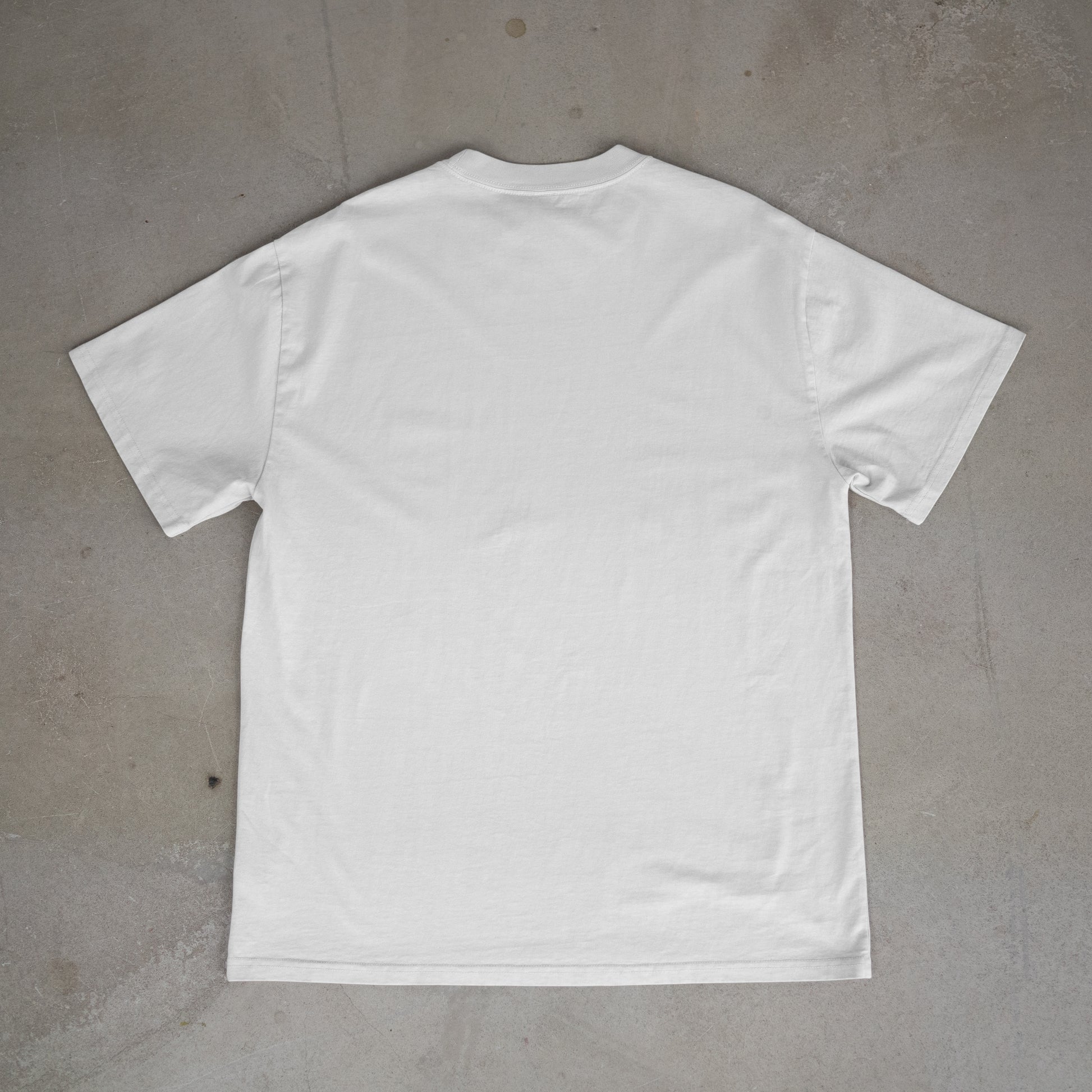 White blank t-shirt (back-side) on a gray concrete surface