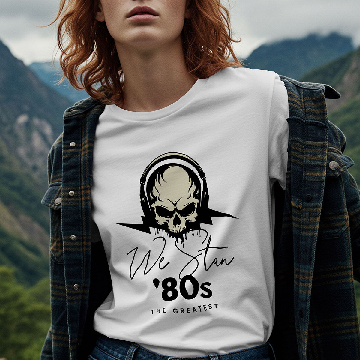 Person wearing a white t-shirt with a skull design and text in a mountainous landscape